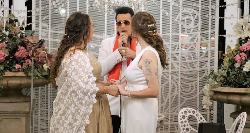 Two brides standing in front of Elvis at A Little White Chapel for their Las Vegas Elopement. 
