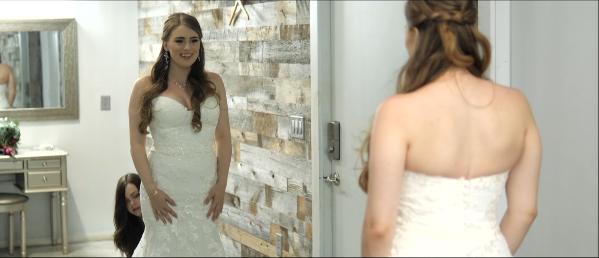 Bride gets ready and looks in mirror by destination wedding videographer