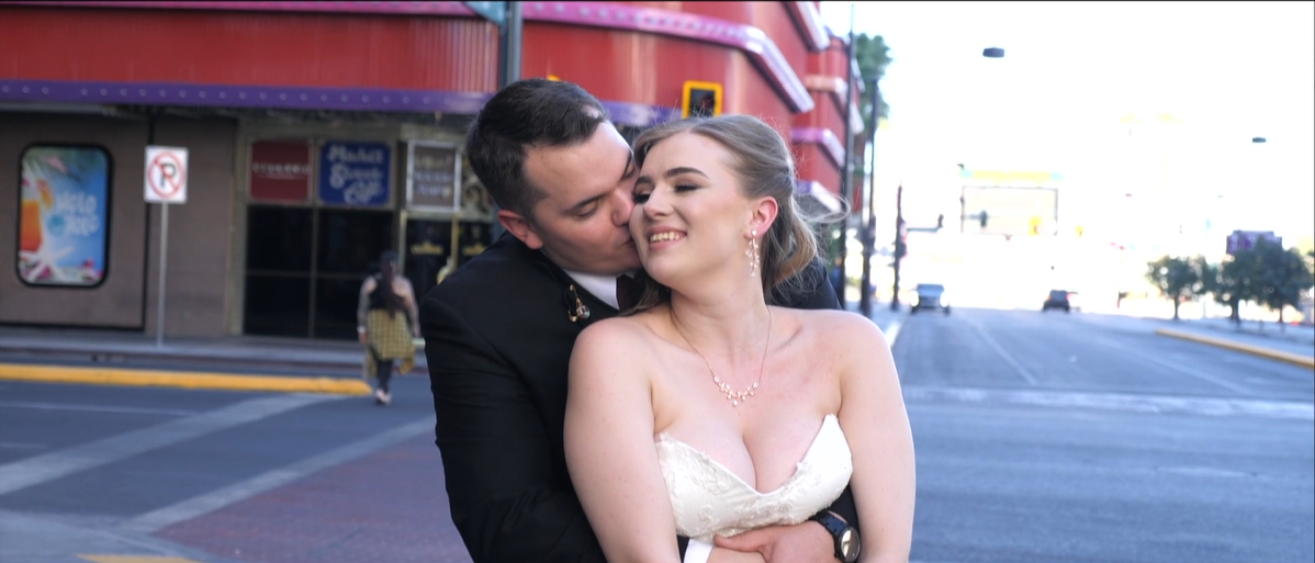 Groom kisses bride and hugs from behind by destination wedding videographer